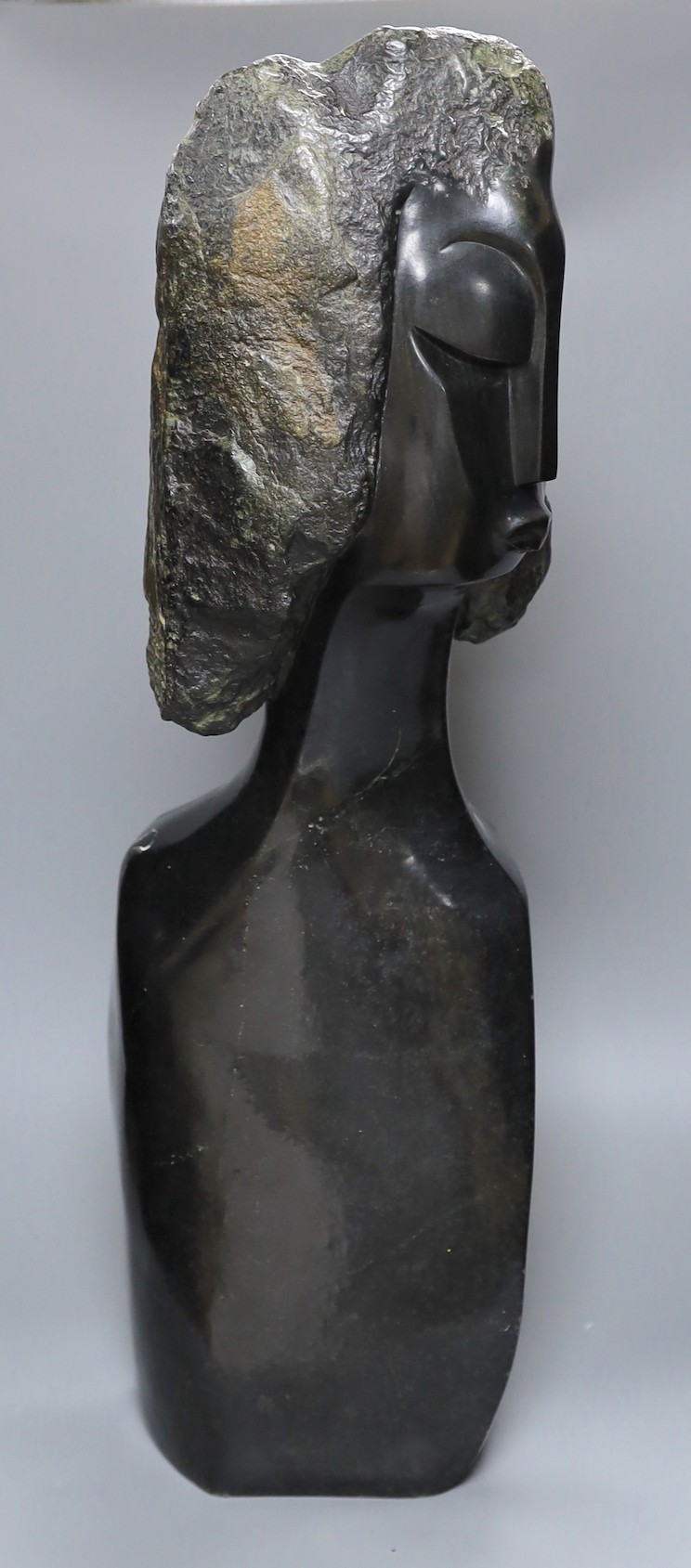 A Zimbabwean carved and polished stone head and upper torso of a woman, 61cms.